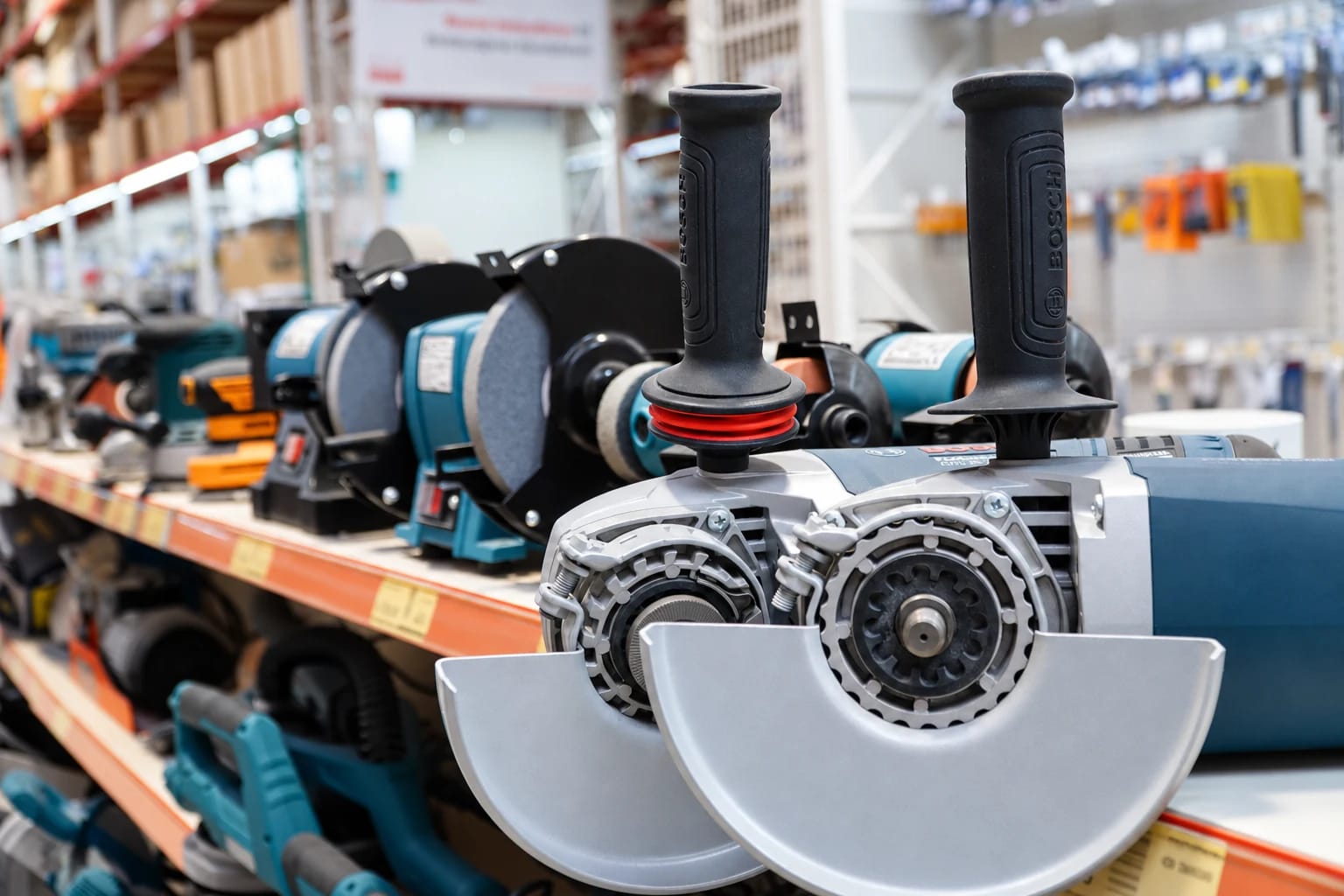 Ön planda avuç taşlama makineleri, arkalarında raf boyunca sıralanan elektrikli el aletleri